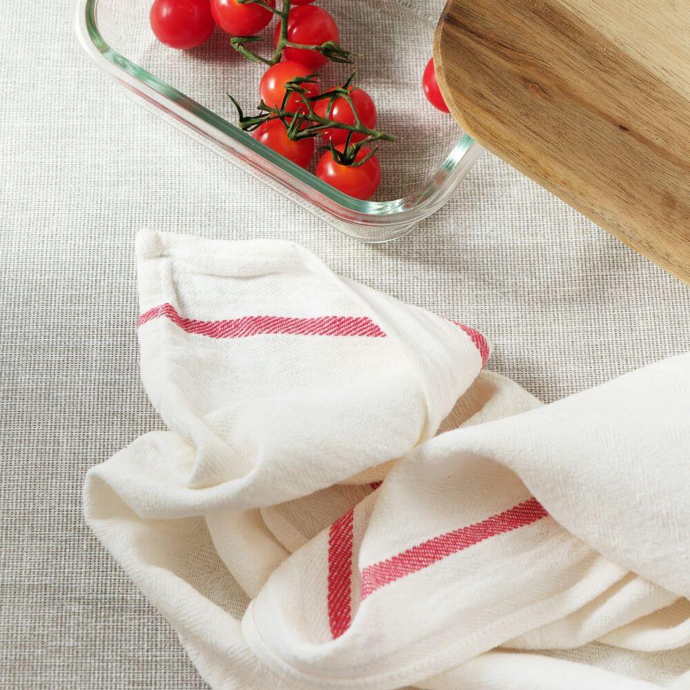 Kitchen Towel beside a bowl of plum tomatoes and Cutting board