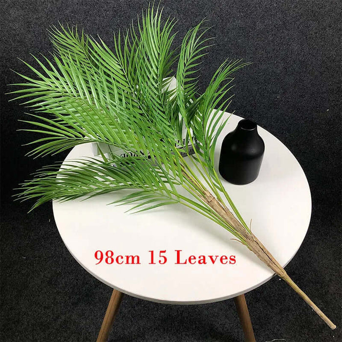 Artificial monstera plants with green leaves displayed on a white table, 98cm tall with 15 leaves.