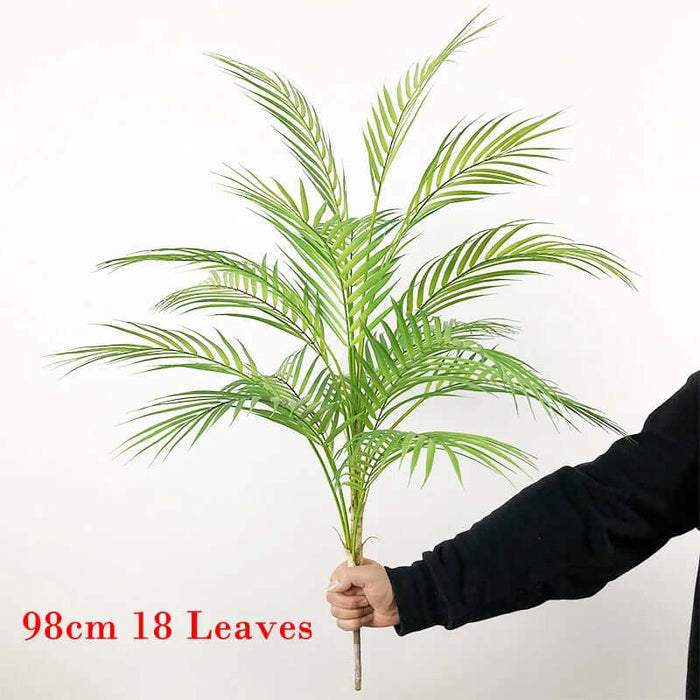 Artificial Monstera plants held by a person, showcasing 18 leaves, elegantly designed for home decor.