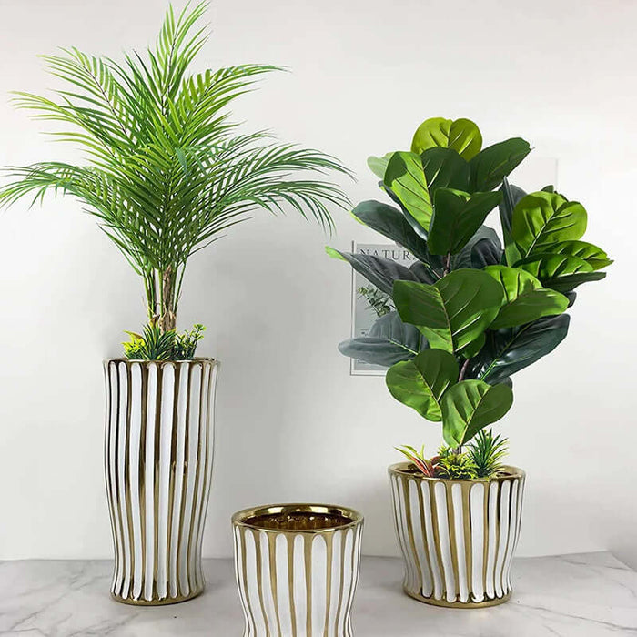 Artificial monstera plants displayed in elegant striped white and gold planters, enhancing home decor.