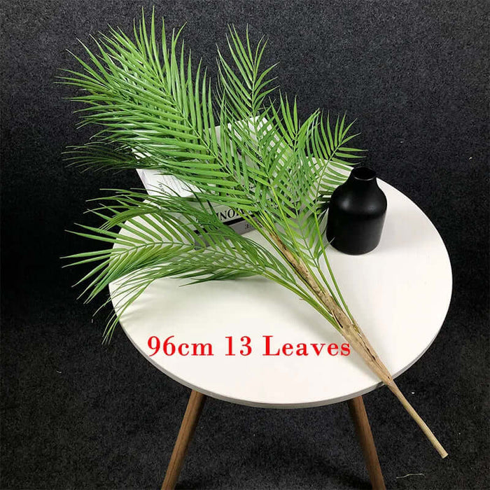 Artificial Monstera plants displayed on a table with a black vase, showcasing 13 green leaves for tropical decor.