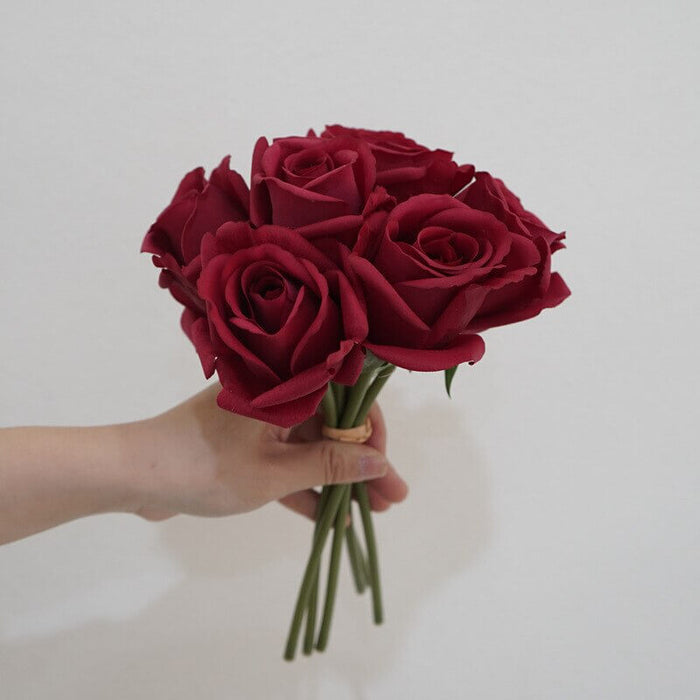 Artificial latex snow mountain rose bouquet in hand, featuring vivid red petals and realistic design.