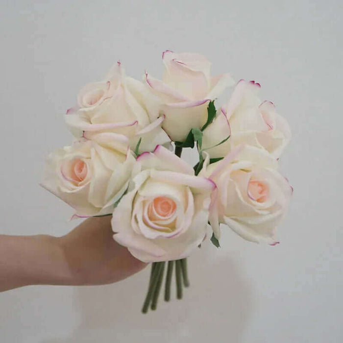 Artificial latex snow mountain rose bouquet held in hand, featuring realistic petals in soft pink and white hues.