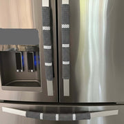 Stainless steel refrigerator with decorative black and white patterned handles in a kitchen setting.