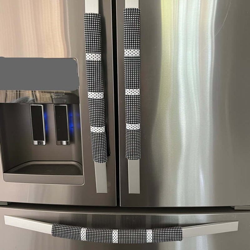 Stainless steel refrigerator with decorative black and white patterned handles in a kitchen setting.