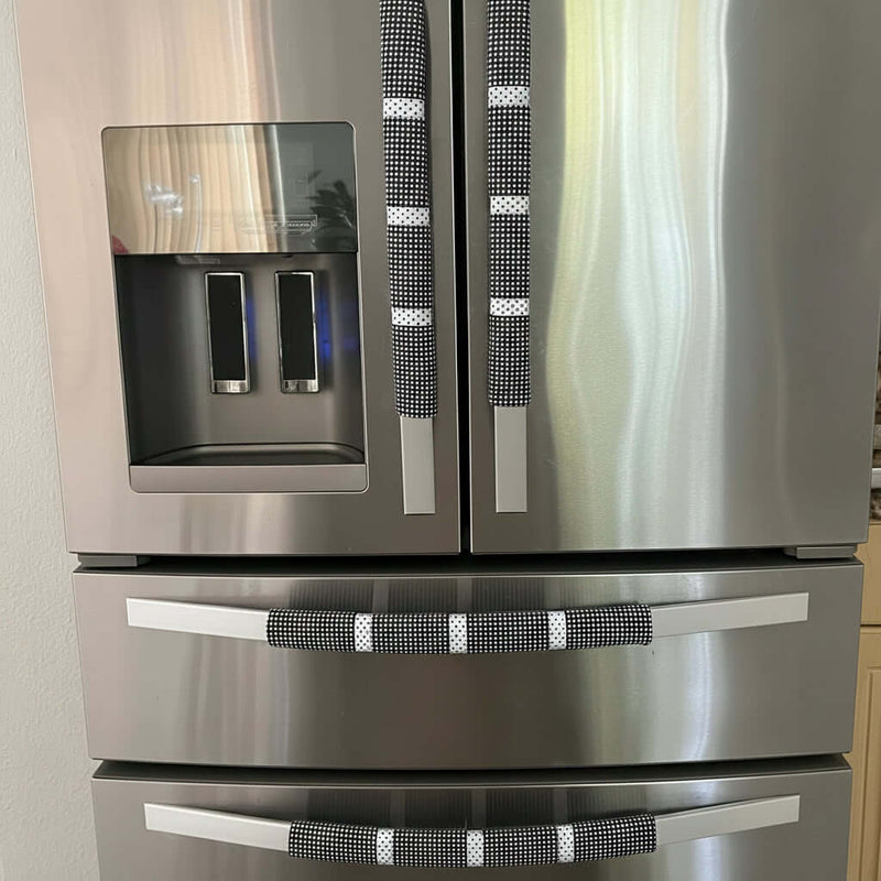 Stainless steel refrigerator with decorative black and white patterned handles in a kitchen setting.