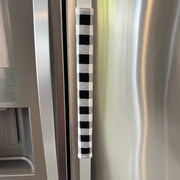 Black and white checkered handle cover on a stainless steel refrigerator door.