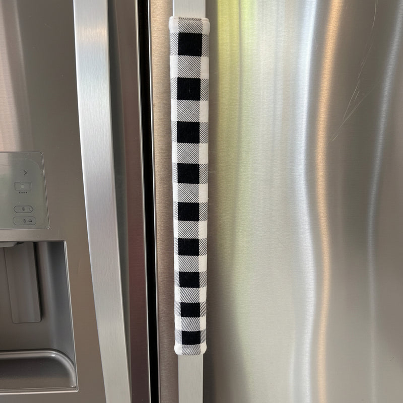 Black and white checkered handle cover on a stainless steel refrigerator door.
