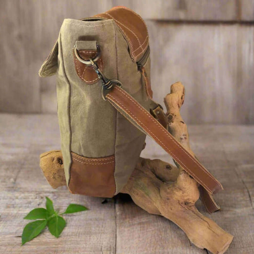 Canvas leather BIPLANE crossbody handbag in tan and khaki, showcased on a rustic wooden background.