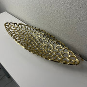 Decorative gold metal tray on a white surface with a light gray wall background