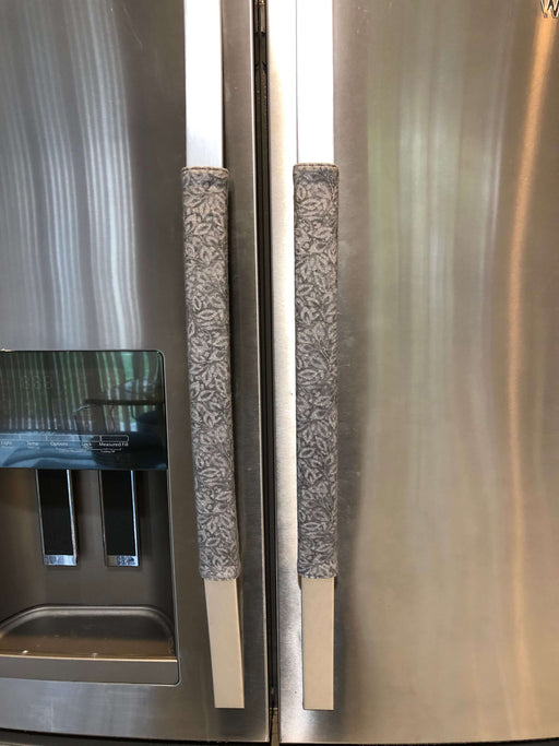 Grey leaf motif appliance handle covers on stainless steel refrigerator for protection and style.