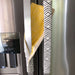 Reversible grey geometric to yellow appliance handle covers on a stainless steel fridge, adding style and protection.