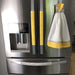 Grey geometric to yellow reversible appliance handle covers on a stainless steel fridge, enhancing kitchen style.