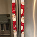 Festive red appliance handle covers with Santa and snowflakes, perfect for holiday kitchen decor.
