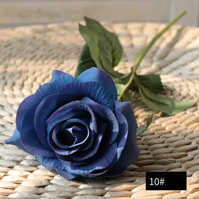 Latex real-touch artificial rose in blue color with realistic texture and details on a woven background.