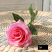 Latex real-touch artificial rose in pink color, showcasing its lifelike appearance and detailed petals on a woven background.