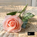 Latex real-touch artificial rose in soft peach color resting on woven surface, highlighting its realistic petals and greenery.