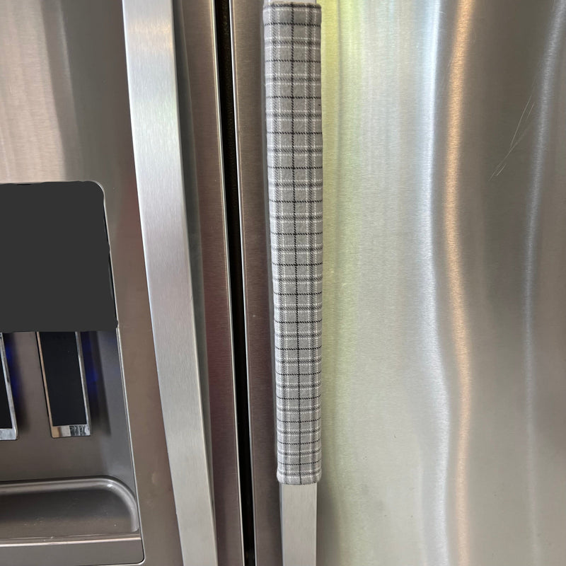 Stainless steel refrigerator with a textured handle made from grey plaid cotton flannel.