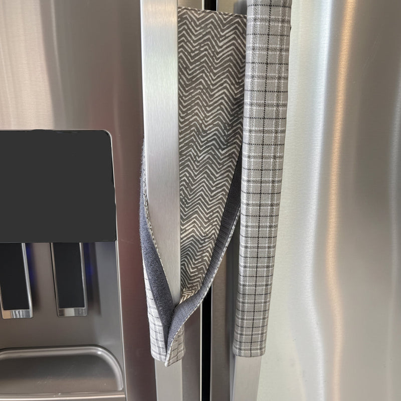 Grey plaid handle cover with a zigzag pattern draped over a fridge handle