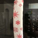 Handmade rose pink snowflake appliance handle cover on a microwave, adding festive decor to the kitchen.