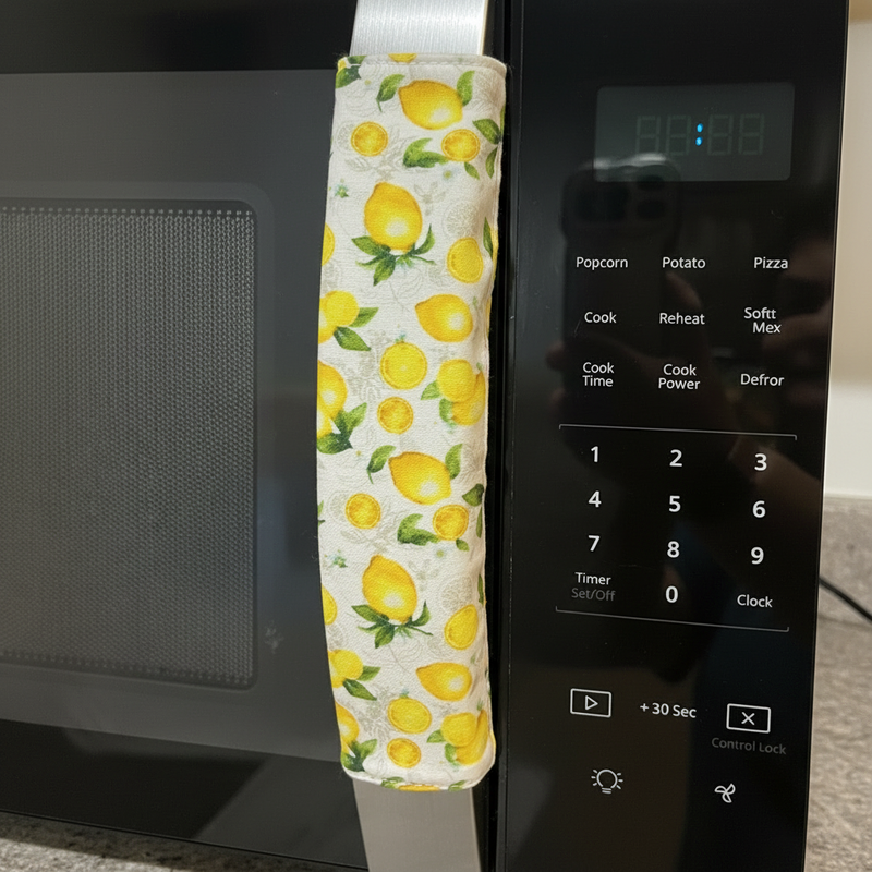 Microwave handle with lemon patterned cover in front of a microwave.
