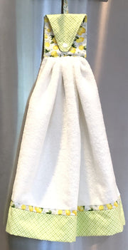 White towel with mint green and yellow trim hanging against a neutral background