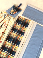 Plaid reversible light blue handle covers with a matching towel and colorful, patterned fabric on a white background.