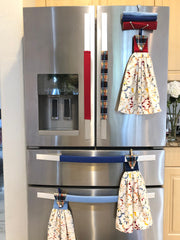Stainless steel fridge with decorative plaid handle covers and hanging towels attached to the handles
