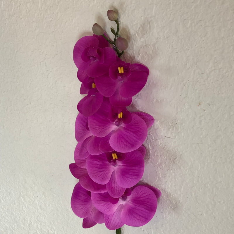 Fuchsia colored  artificial orchid on a textured white background