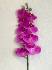 Fuchsia colored artificial orchid on a textured white background