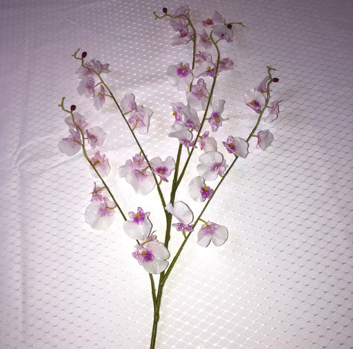 Artificial dancing lady orchid branch on a textured white background