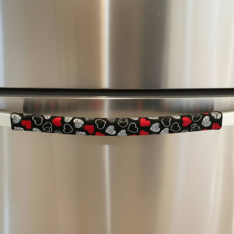 Red and white hearts on black Valentine-themed appliance handle covers on a refrigerator handle.