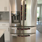 Red and white hearts on black Valentine-themed appliance handle covers on a stainless steel fridge.