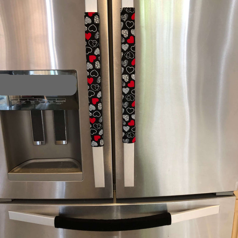 Red and white hearts on black Valentine-themed appliance handle covers on a refrigerator.