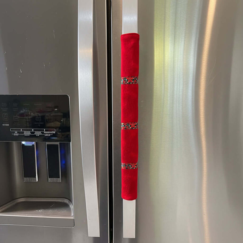 Red flannel handle cover with decorative elements on a fridge.