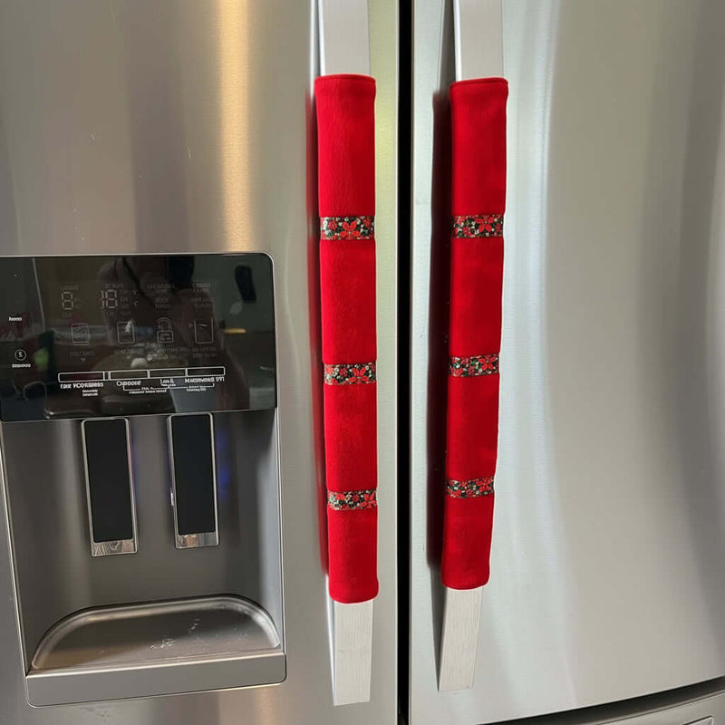 Red flannel door handle covers with poinsettia ribbon trim on a stainless steel fridge.