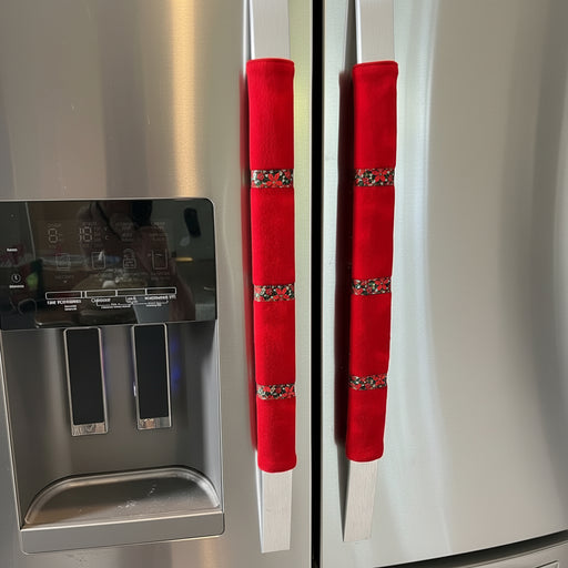 Red flannel door handle covers with poinsettia ribbon trim on a stainless steel fridge.
