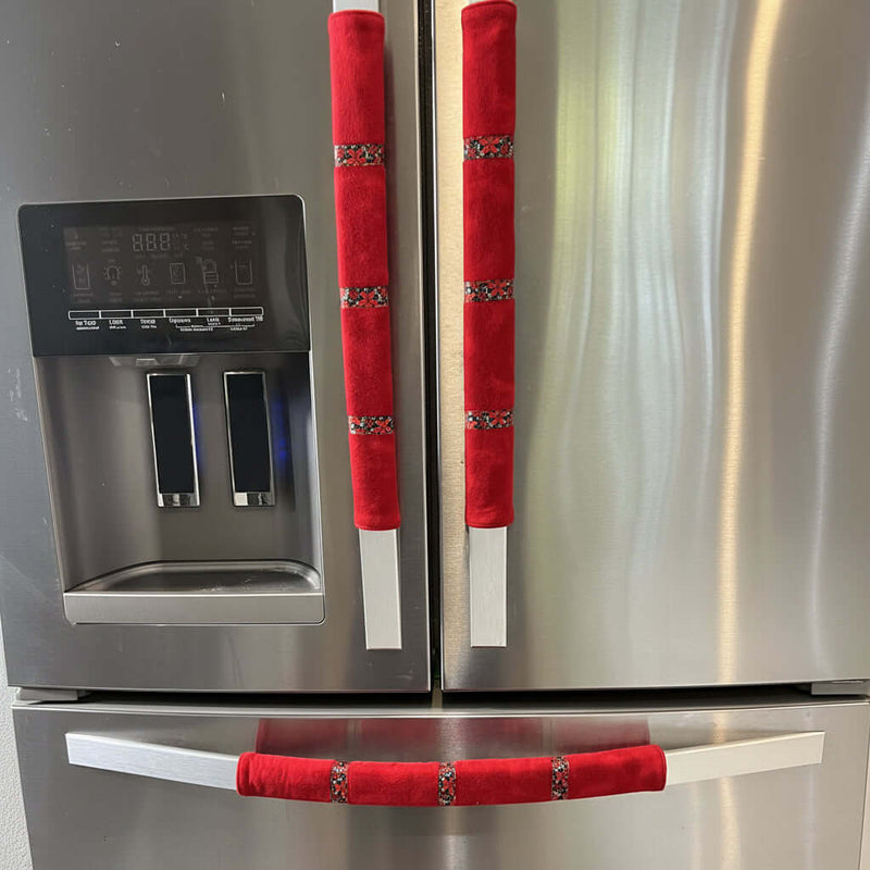 Stainless steel refrigerator with red handle covers featuring poinsettia ribbon decorative elements.