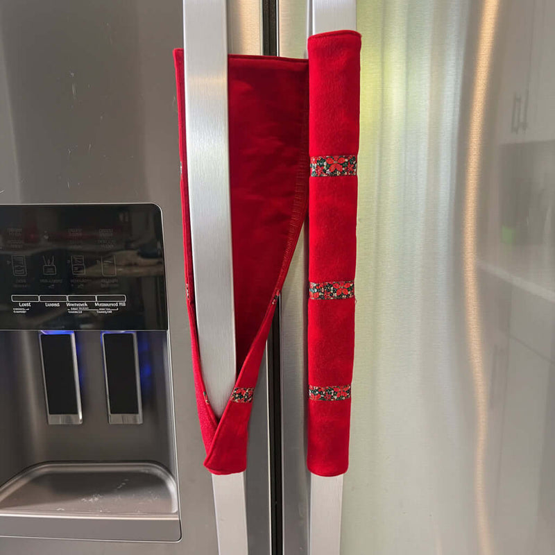 Red handle cover with decorative patterns on a stainless steel fridge.