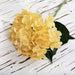 Yellow latex hydrangea artificial flowers with green leaves on a wooden background, realistic and hypo-allergenic.