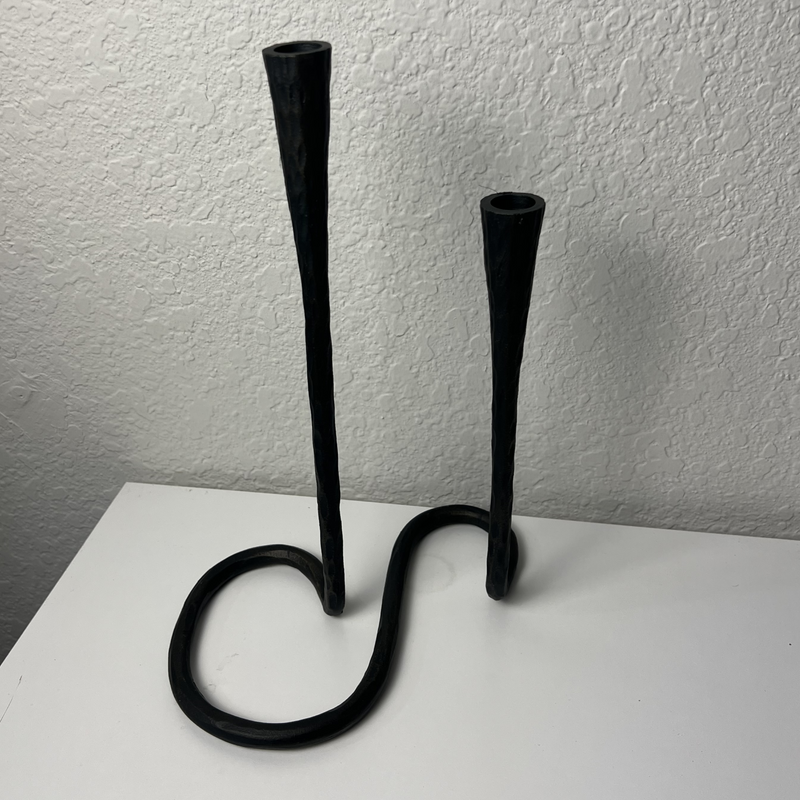 Black metal candle holder on a white surface with a plain background