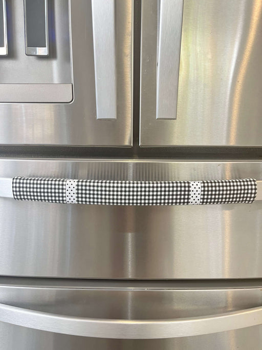 Black and white buffalo plaid handle cover on a stainless steel refrigerator, enhancing kitchen decor.