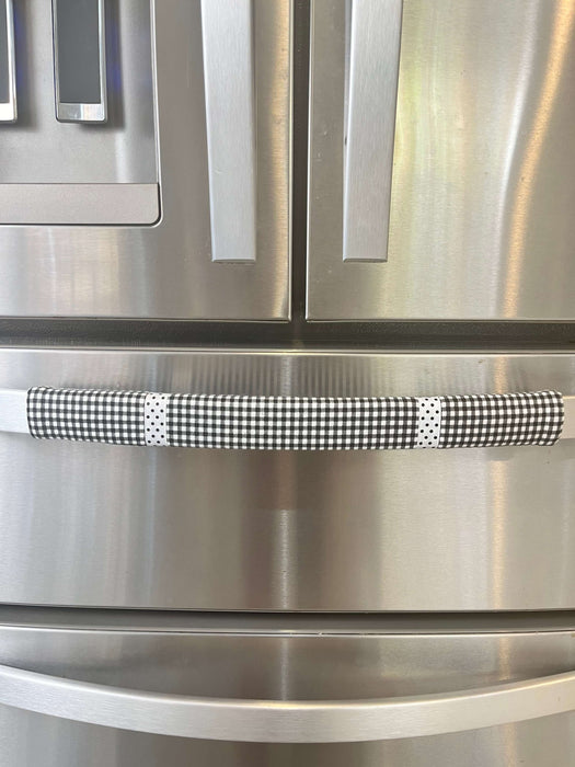 Black and white buffalo plaid handle cover on a stainless steel refrigerator, enhancing kitchen decor.