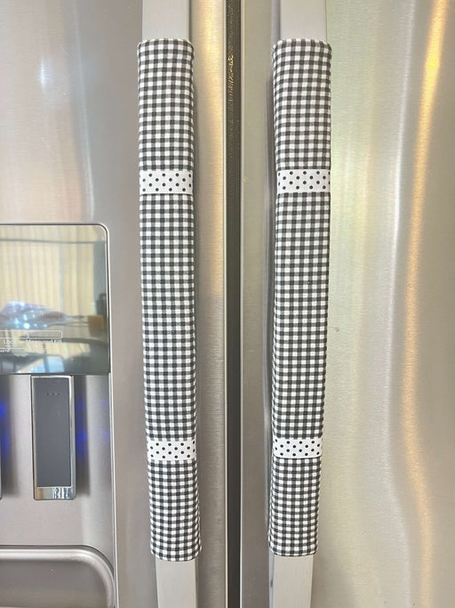 Stylish black and white buffalo plaid handle covers on refrigerator handles for decorative kitchen protection.