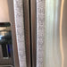 Grey and white gerbera daisy handle covers on stainless steel refrigerator doors, providing style and protection.