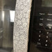Grey and white gerbera daisy handle cover on a stainless steel refrigerator door.