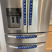 Blue appliance handle covers with white snowflakes on a stainless steel fridge.
