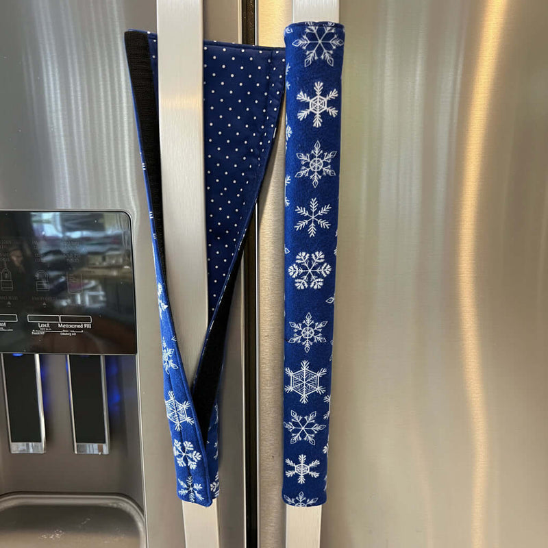 Two blue fabric handle covers with snowflake patterns on fridge handles.