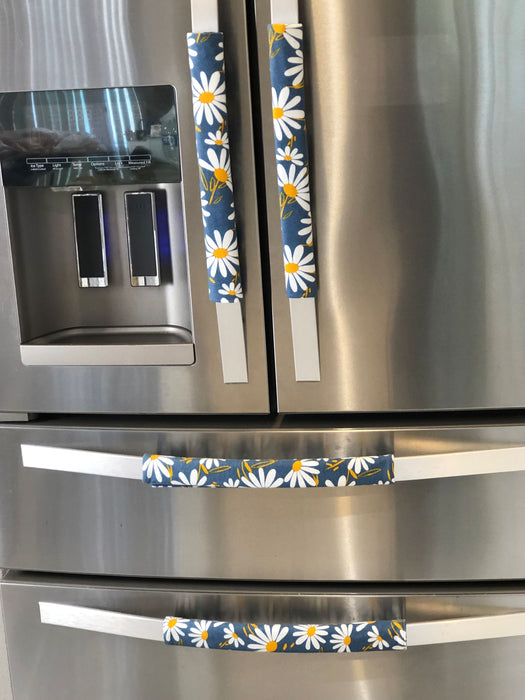 Stylish blue appliance handle covers featuring white and yellow daisies, adding modern décor and protection.