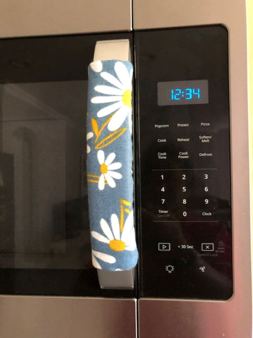 White and yellow daisy appliance handle cover on microwave, enhancing decor and protecting handles from scratches.